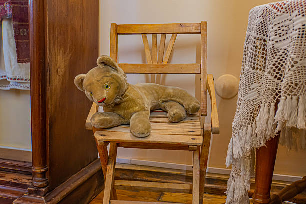 A vintage rocking chair with a worn teddy bear in a cozy, possibly old-fashioned setting