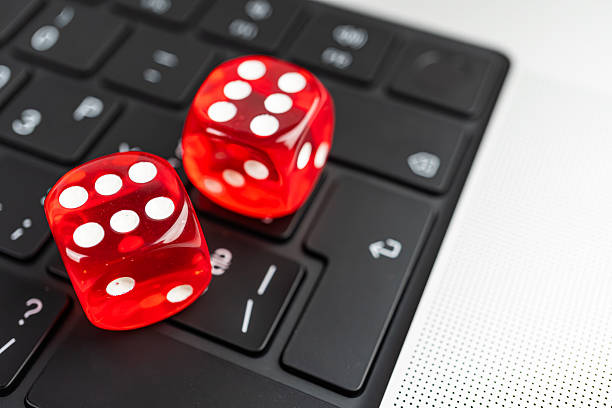 istock Image depicts two red dice on a black keyboard with white lettering, possibly suggesting the blend of physical and virtual worlds in a gaming or gambling context 2211346528