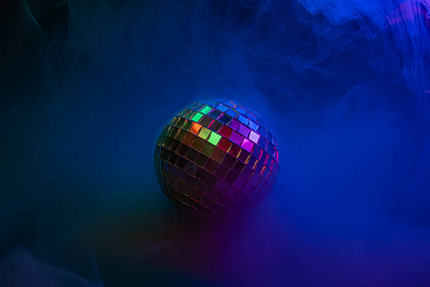 istock Disco ball with multicolored lights and blue smoke against a party backdrop, evoking nostalgia for the disco era, fun, and celebration 2211346557