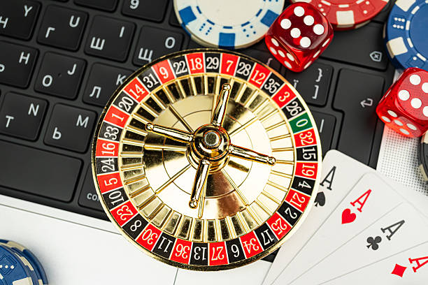istock Image showcases a vintage roulette wheel surrounded by playing cards, chips, and a keyboard with Cyrillic letters, suggesting a Russian casino theme 2211346648
