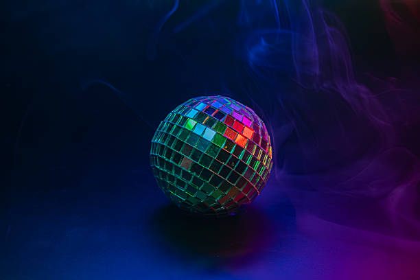 istock Disco ball on dark surface, reflecting colorful lights and soft smoke effects against a party or festive background 2211346688