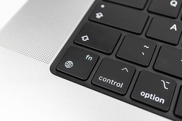 Close-up photo of a modern keyboard, labeled keys with white text on black background, function keys like control and option, matte finish suggesting rubber dome or mechanical switches, tactile f