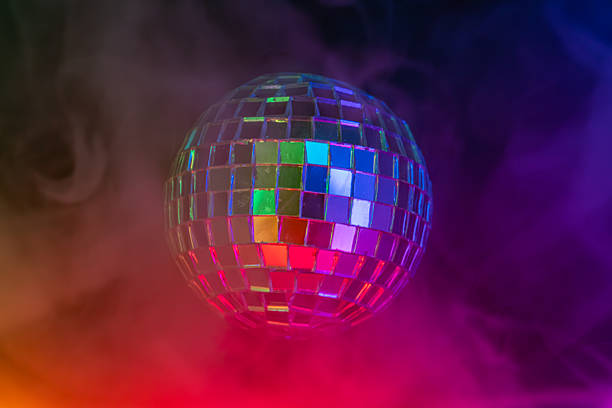 istock Image of a disco ball against a vibrant gradient backdrop purple to orange, reflecting lights in a festive or celebratory atmosphere, commonly symbolizing fun and lively gatherings 2211346869