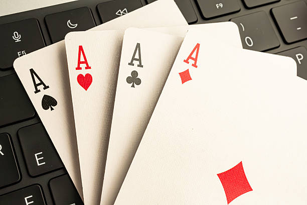 istock Image displays four Aces from a deck of playing cards before a computer keyboard, symbolizing themes related to technology, gaming, or strategy 2211346916