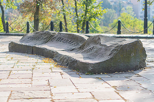 A serene park scene with a weathered stone bench, blending into rustic brick pavers and grass Tall trees in the background add natural charm, suggesting tranquility amidst urban landscapes