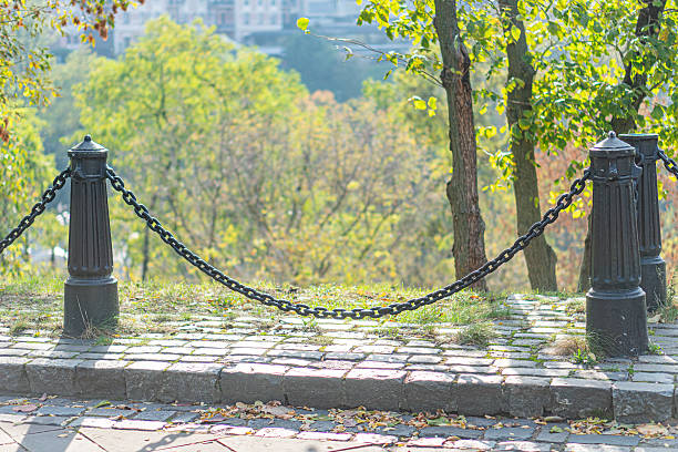 istock Image shows a serene, inviting hillside park path ascending a green hill The sturdy black metal railing offers security for a peaceful walk amidst autumnal tree-lined greenery 2211348343