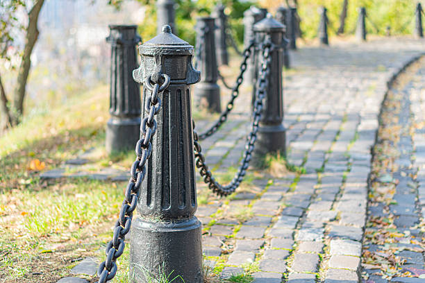 istock An inviting, tranquil outdoor scene featuring a brick pathway lined with black wrought iron poles and chains The image suggests an urban park or garden area in autumn, showcasing harmony between nat 2211348410