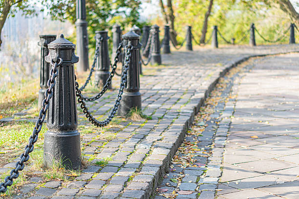 istock A charming brick pathway with contrasting greenery, black metal posts, scattered autumn leaves, and towering trees in a tranquil park setting, perfect for leisurely strolls 2211348430
