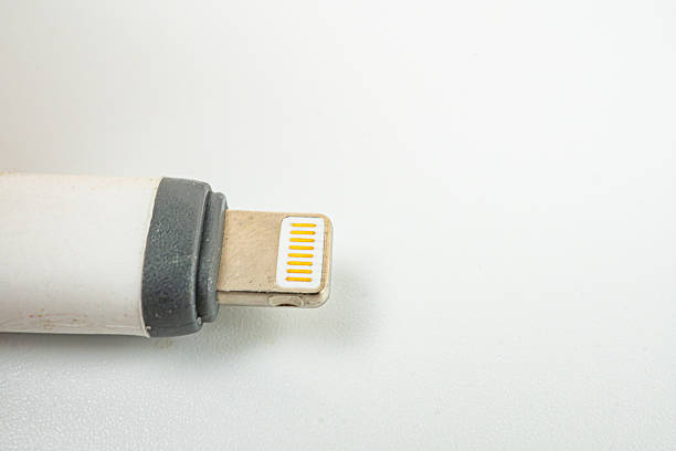 istock Close-up black and white image of a well-used silver Apple Lightning cable, showcasing its robust design, frequent use, and essential role as a tech accessory 2211348625