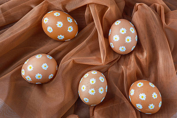 Decoratively painted eggs resting on a soft orange fabric background