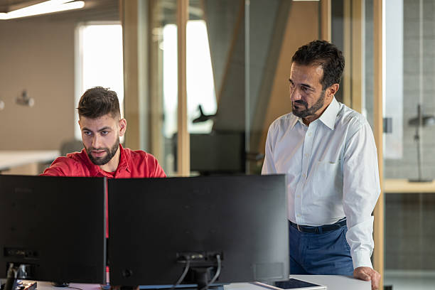 istock Young And Senior Professionals Collaborating At Computer Workstation In Modern Office Environment 2211349336