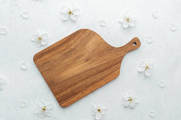 istock Wooden cutting board placed on white surface with delicate flowers around 2211349502