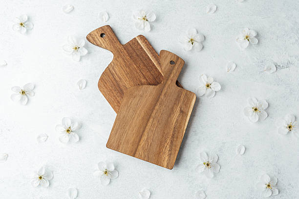 istock Wooden cutting boards arranged on a light surface with flower accents 2211349505