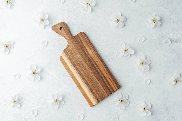 istock Wooden cutting board surrounded by white flowers on a light surface 2211349506