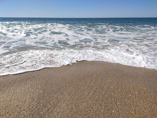 istock Serene ocean scene. Gentle waves wash over the sandy beach. Evokes tranquility  relaxation. Perfect for travel, coastal living or summer themes. 2211349568