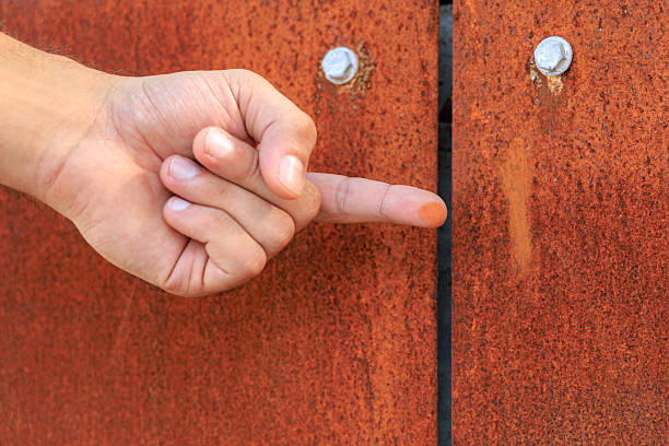 A hand pointing at a rusty door. The hand is raised and the finger is pointing at the door, corten steel