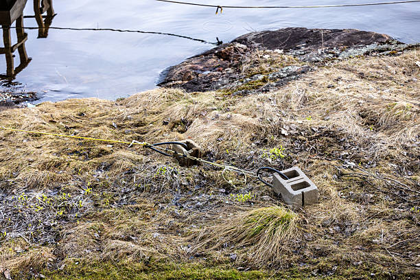 istock Rope Secured with Concrete Blocks by a Rocky Lakeside 2211352895