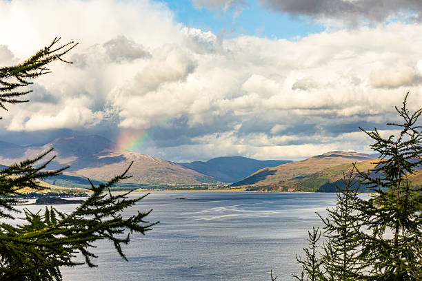 istock Scenic Highland Lake Surrounded by Mountains with Rainbow and Dramatic Clouds 2211354833