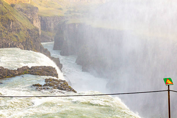 A stunning waterfall showcases its powerful flow through rugged cliffs, enveloped in mist, creating a serene yet powerful landscape. The scene is a testament to nature's raw beauty and grandeur.