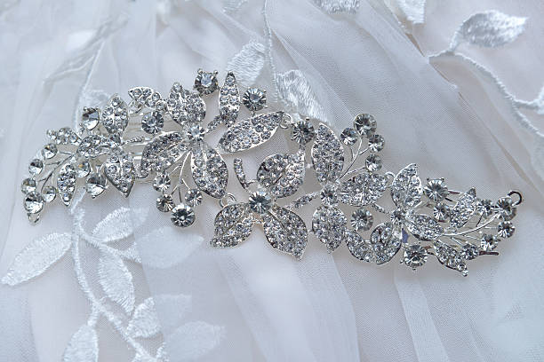 A close-up of a silver bridal hairpiece adorned with shimmering crystals. Captured with a macro lens and directional lighting to emphasize the craftsmanship, this accessory rests gently on a soft ivory fabric. The image exudes elegance and showcases bridal refinement.