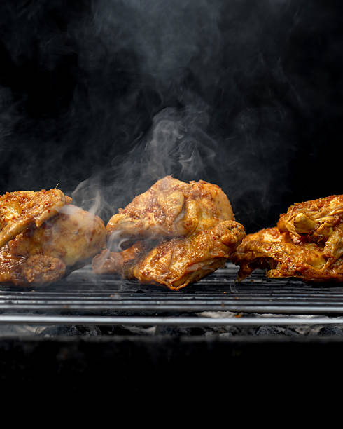 istock Three pieces of chicken are on a grill, with smoke coming from them 2211357262