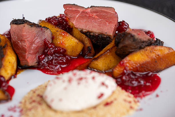 istock Roasted duck breast resting on caramelized apple slices, garnished with cranberry sauce, plated with cream cheese crumbs, highlighting refined culinary artistry 2211359988