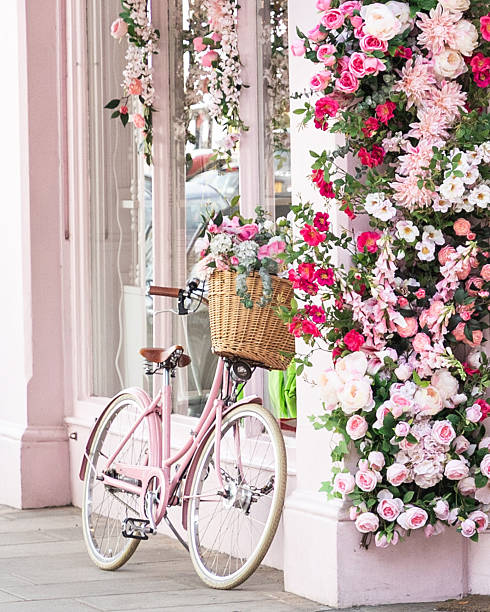 Pink bicycle leaning up against a pink wall with a wicker basket and pink flower garland