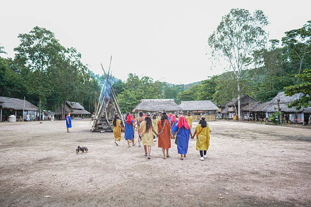 Chanchamayo, Peru, December 30, 2020: A vibrant traditional dance ceremony performed by an indigenous community in Chanchamayo, Peru, during the COVID-19 pandemic. The image shows both locals and visitors wearing face masks, engaging in a cultural exchange while preserving ancestral traditions. Surrounded by thatched huts and lush jungle, this scene highlights the resilience and cultural pride of Amazonian communities in challenging times.