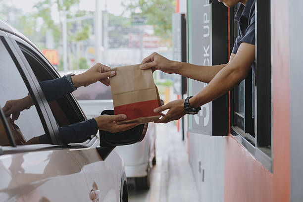istock A customer picks up coffee in his car during rush hour from a drive-thru employee. 2211363723