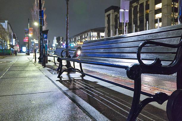 istock bench on the rainy street 2211367120