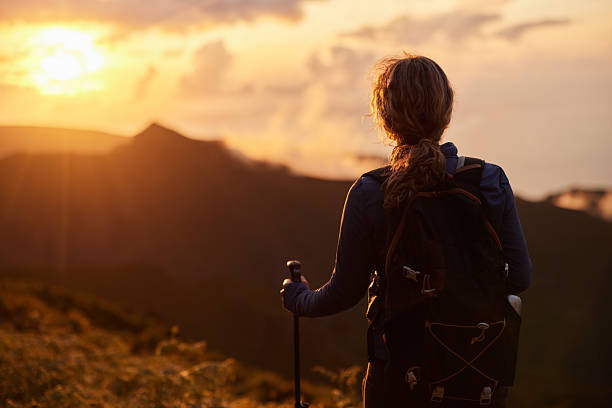 istock Back view of a female backpacker looking at sunset view from a mountain. 2211379972