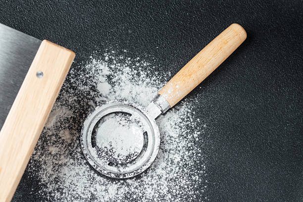 istock Flour scattered beside a metal sifter on a dark surface in a kitchen 2211380174