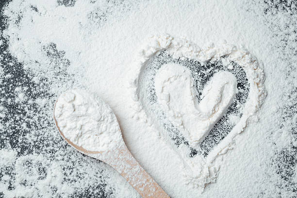 istock Flour heart shape created on a dark surface with a spoon nearby 2211380184