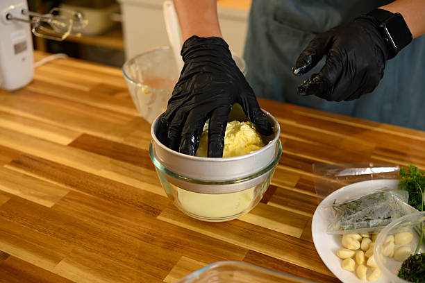 istock Gloved hands squeezing creamy butter over bowl, releasing fresh buttermilk 2211381550
