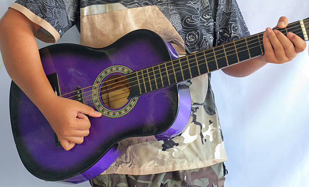 a person’s hand strumming strings on a vibrant purple acoustic guitar, creating artistic and musical ambiance
