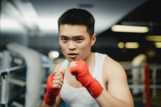 istock The young Asian boxer is looking at the camera on the boxing ring 2211388709
