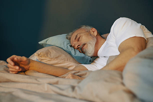 istock Elderly Man Sleeping Peacefully in Bed With Pillows 2211389211