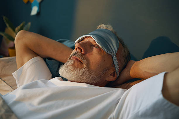 istock Relaxed Elderly Man Reclining with Sleep Mask in Bed 2211389217