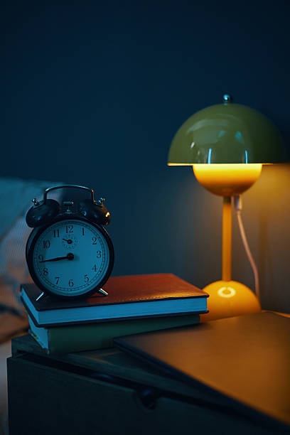 istock Illuminated Vintage Alarm Clock on Bedside Table 2211389320