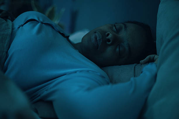 istock Sleeping African American Woman in Soft Blue Lighting 2211389323