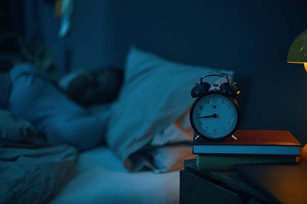istock Sleeping Person with Alarm Clock Showing Early Morning Time 2211389328