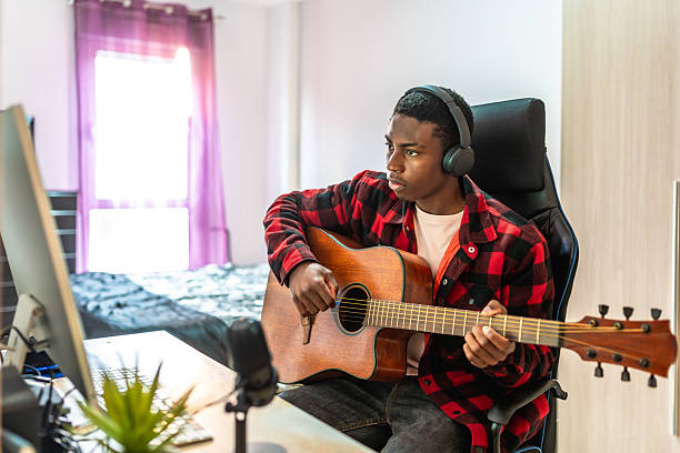 istock Young musician composing music playing acoustic guitar at home studio 2211390953