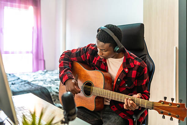 istock Young musician composing music at home with guitar and microphone 2211390954