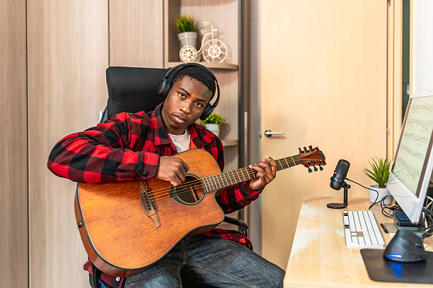 istock Young musician composing music playing acoustic guitar at home studio 2211391009