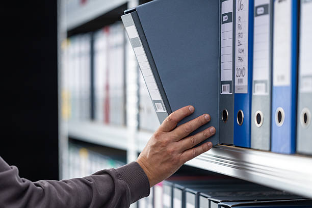 Close-up of human hand searching file folder in office.