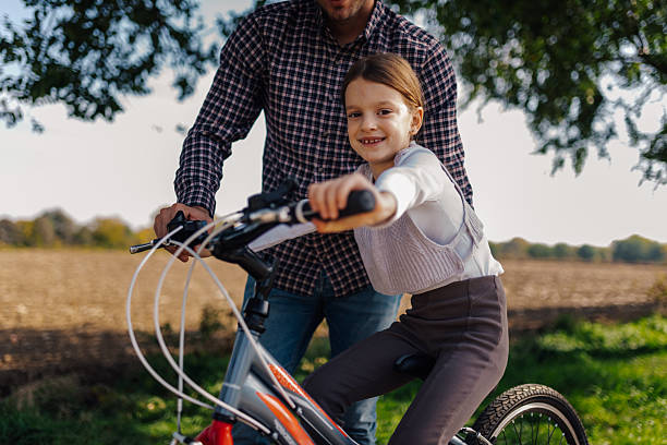 istock Father teaching daughter riding bicycle in countryside 2211398684