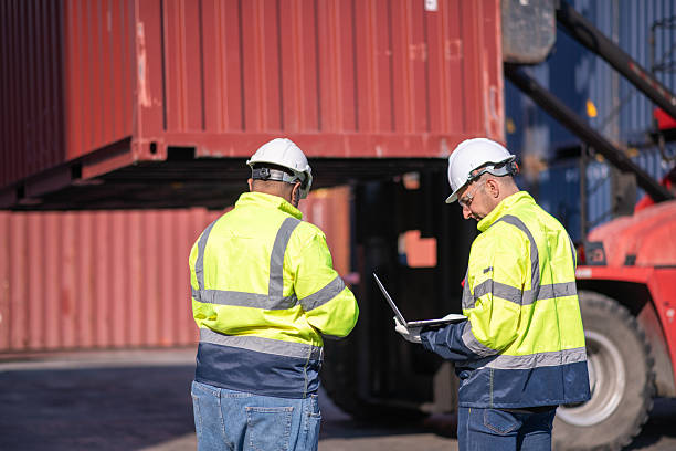 istock Dock worker or engineer overseeing operations logistics and shipping yard managing inventory, shipping schedules, or container tracking technology, and safety in the shipping industry, depicting a professional in action at a container yard. 2211399956