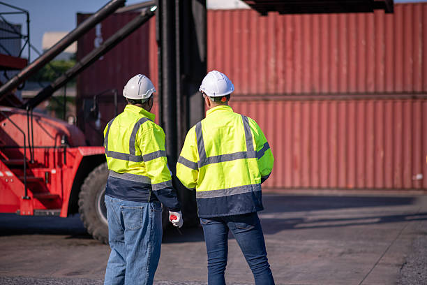 istock Dock worker or engineer overseeing operations logistics and shipping yard managing inventory, shipping schedules, or container tracking technology, and safety in the shipping industry, depicting a professional in action at a container yard. 2211399962
