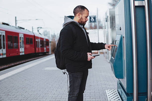 istock Traveler using ticket machine at train station. Man buying a ticket 2211402292