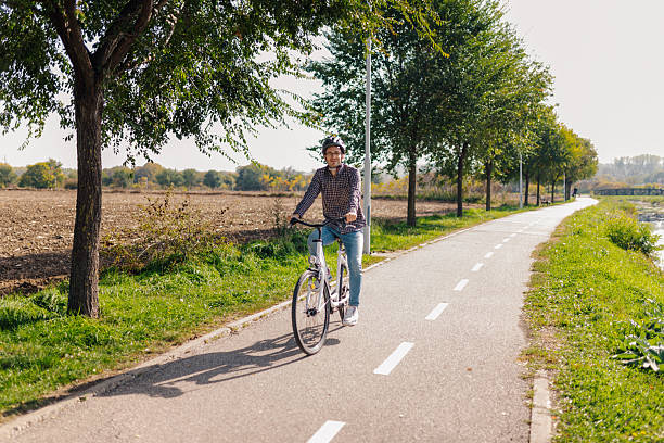 istock Young man riding bicycle in a park near a river 2211402982